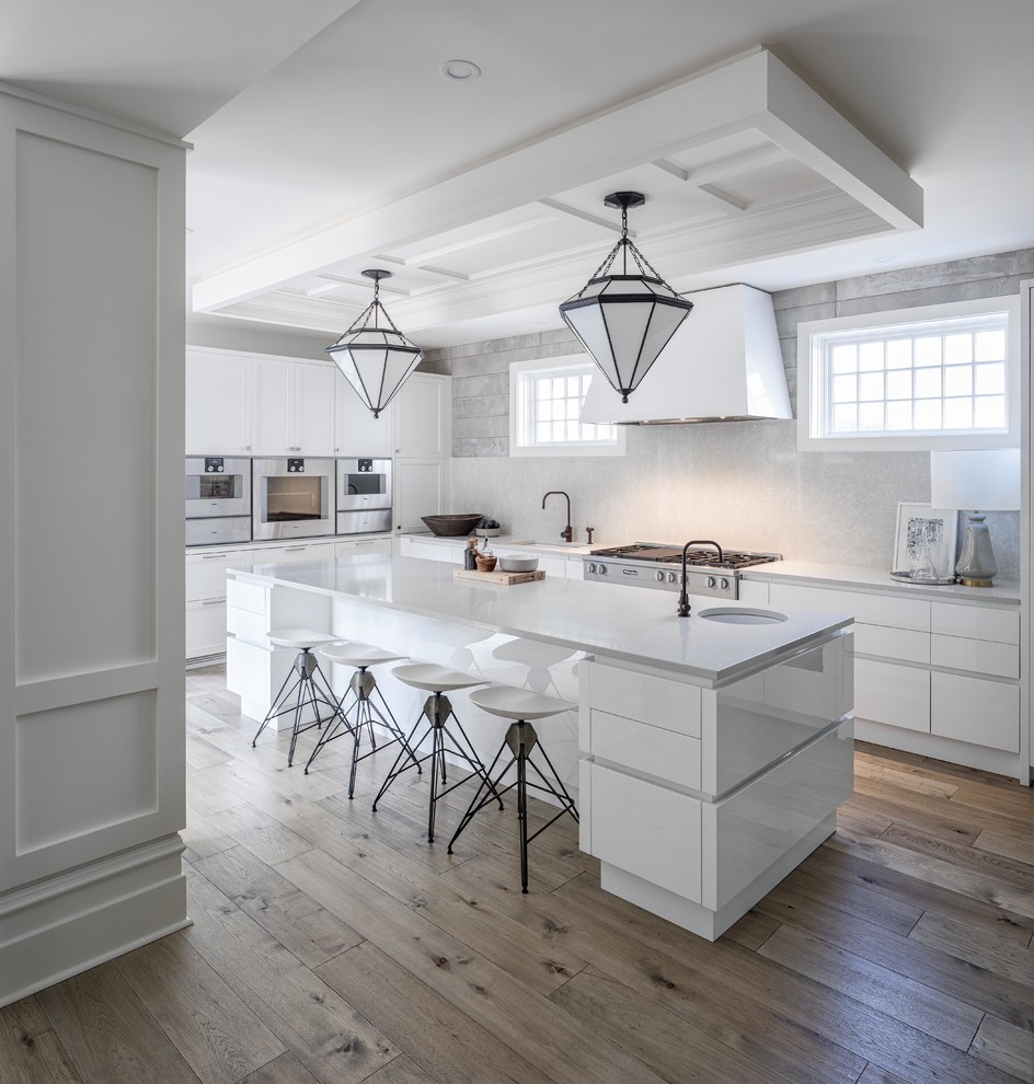 Inspiration for a large contemporary l-shaped kitchen/diner in Ottawa with a single-bowl sink, flat-panel cabinets, white cabinets, quartz worktops, white splashback, stone slab splashback, stainless steel appliances, light hardwood flooring and an island.