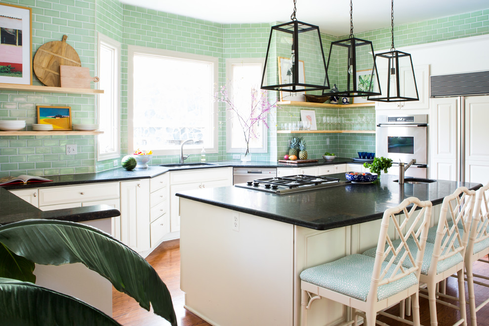 Inredning av ett modernt kök, med vita skåp, grönt stänkskydd, stänkskydd i keramik och en köksö