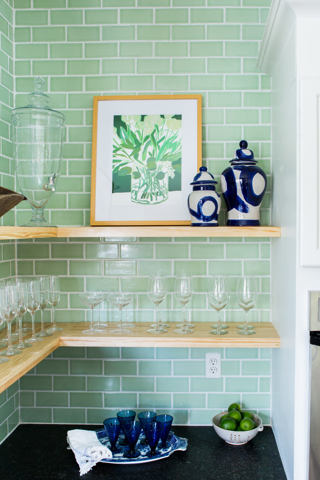 Modern inredning av ett kök, med vita skåp, grönt stänkskydd, stänkskydd i keramik och en köksö