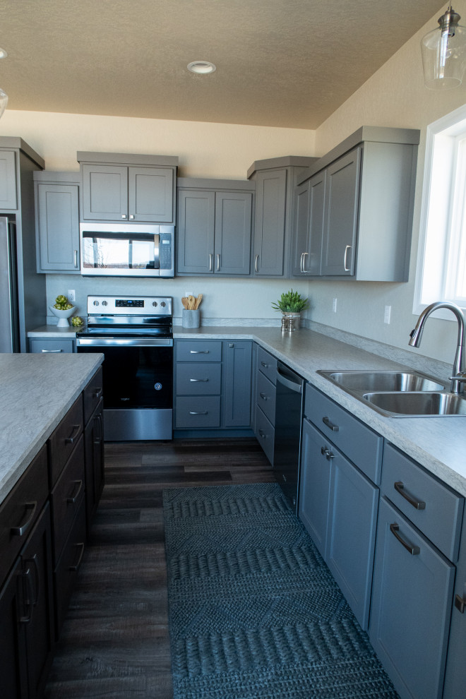 Immagine di una cucina chic con lavello da incasso, ante in stile shaker, ante grigie, top in laminato, elettrodomestici in acciaio inossidabile, pavimento in vinile, pavimento marrone e top beige