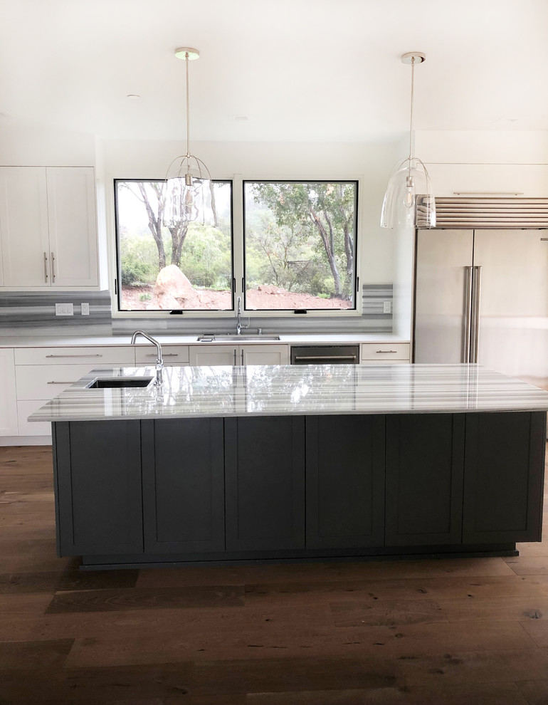 Inspiration for an expansive contemporary u-shaped open plan kitchen in Santa Barbara with a submerged sink, shaker cabinets, white cabinets, marble worktops, multi-coloured splashback, marble splashback, stainless steel appliances, medium hardwood flooring, an island, brown floors and multicoloured worktops.