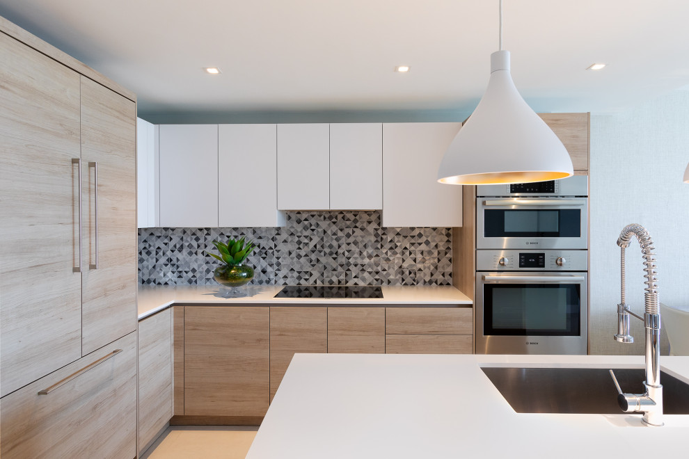 Moderne Küche in L-Form mit Unterbauwaschbecken, flächenbündigen Schrankfronten, hellen Holzschränken, Küchenrückwand in Grau, Küchengeräten aus Edelstahl, Kücheninsel, beigem Boden und weißer Arbeitsplatte in Miami