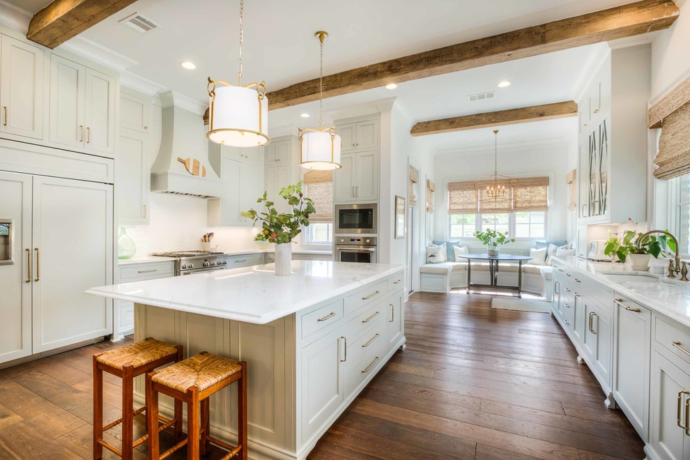 Photo of a large traditional open plan kitchen in New Orleans with a submerged sink, beaded cabinets, grey cabinets, marble worktops, white splashback, ceramic splashback, stainless steel appliances, medium hardwood flooring, an island, brown floors and white worktops.