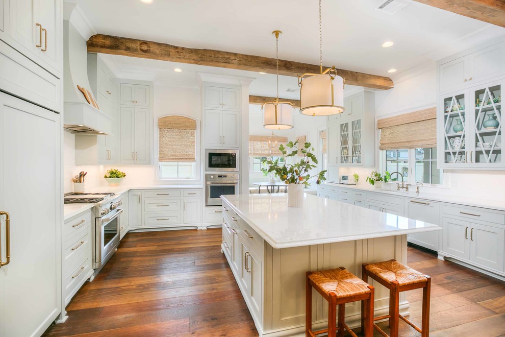 This is an example of a large coastal kitchen in New Orleans with a submerged sink, grey cabinets, marble worktops, white splashback, ceramic splashback, stainless steel appliances, medium hardwood flooring, an island, brown floors, white worktops and shaker cabinets.