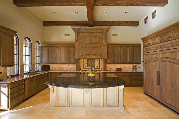 Example of a large tuscan u-shaped ceramic tile open concept kitchen design in Phoenix with an undermount sink, raised-panel cabinets, dark wood cabinets, granite countertops, beige backsplash, ceramic backsplash, paneled appliances and an island