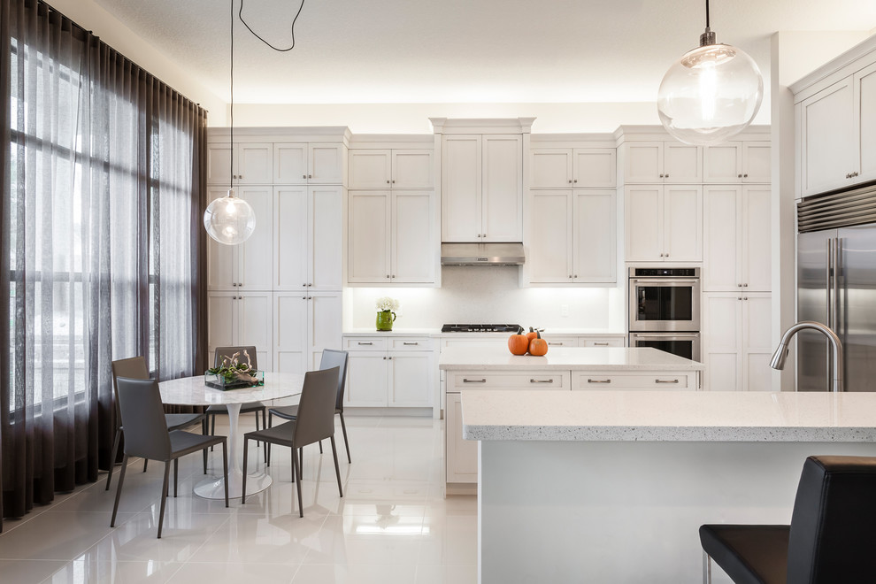 Große Klassische Wohnküche mit Schrankfronten mit vertiefter Füllung, weißen Schränken, Küchenrückwand in Weiß, Küchengeräten aus Edelstahl und zwei Kücheninseln in Miami