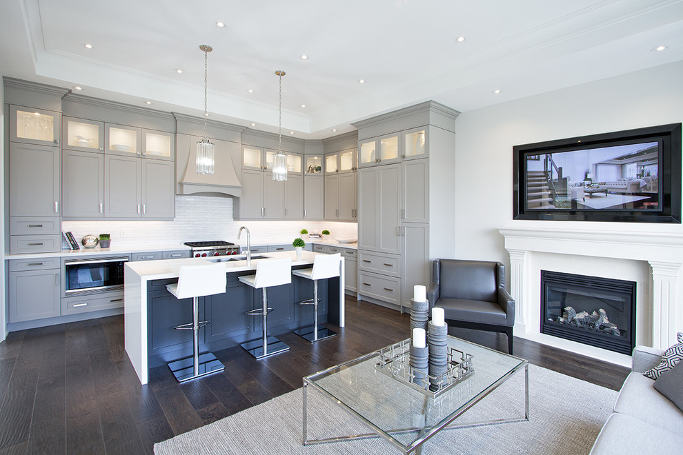 Mittelgroße Moderne Wohnküche in L-Form mit Unterbauwaschbecken, Schrankfronten im Shaker-Stil, grauen Schränken, Küchenrückwand in Weiß, Rückwand aus Metrofliesen, Kücheninsel, weißer Arbeitsplatte und dunklem Holzboden in Toronto