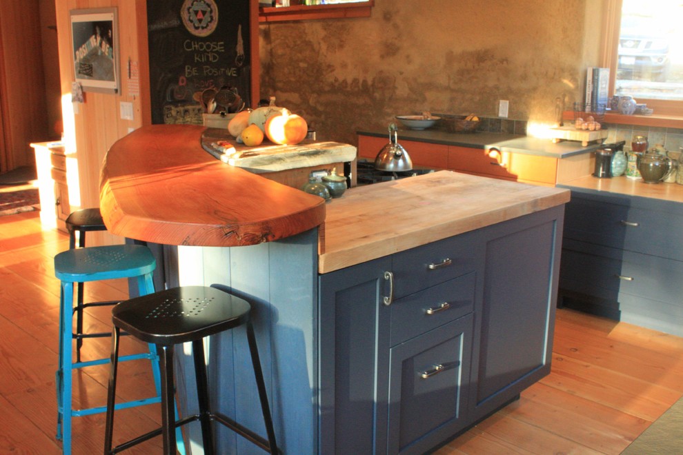 Inredning av ett lantligt mellanstort kök, med en rustik diskho, skåp i shakerstil, blå skåp, träbänkskiva, grönt stänkskydd, stänkskydd i keramik, rostfria vitvaror, ljust trägolv, en köksö och brunt golv