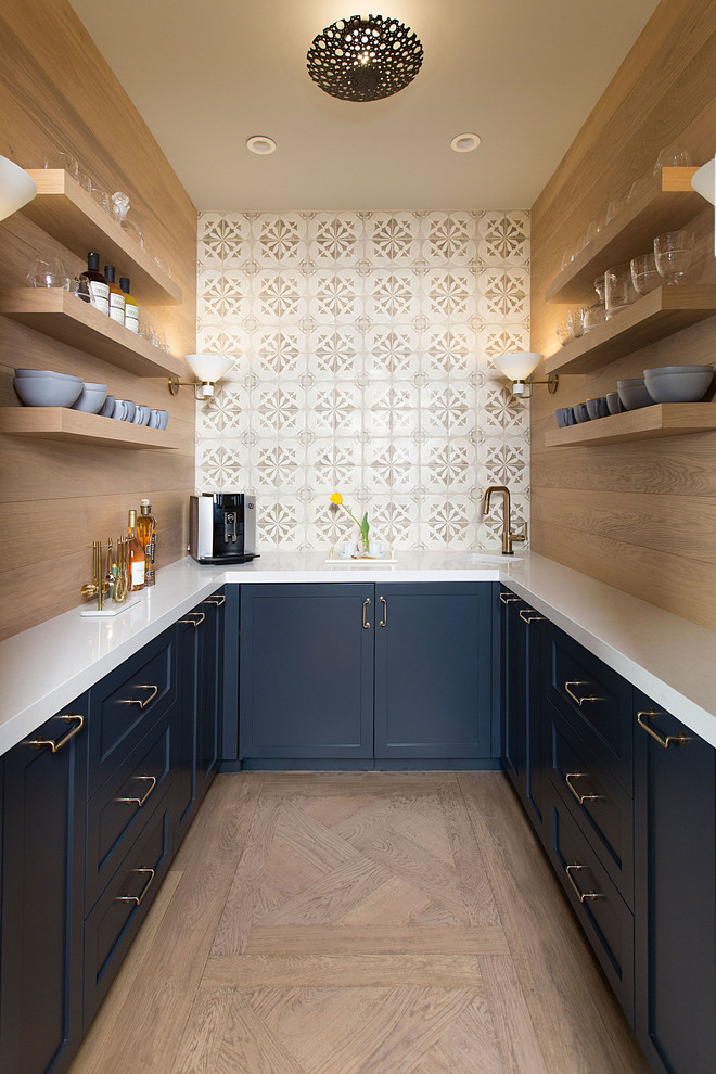 Inspiration for a transitional u-shaped medium tone wood floor and brown floor kitchen pantry remodel in Chicago with an undermount sink, shaker cabinets, blue cabinets, no island, white countertops and beige backsplash