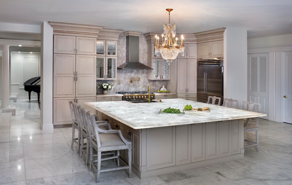 Inredning av ett klassiskt stort vit vitt kök, med en rustik diskho, luckor med upphöjd panel, skåp i ljust trä, marmorbänkskiva, beige stänkskydd, rostfria vitvaror, marmorgolv, en köksö och vitt golv
