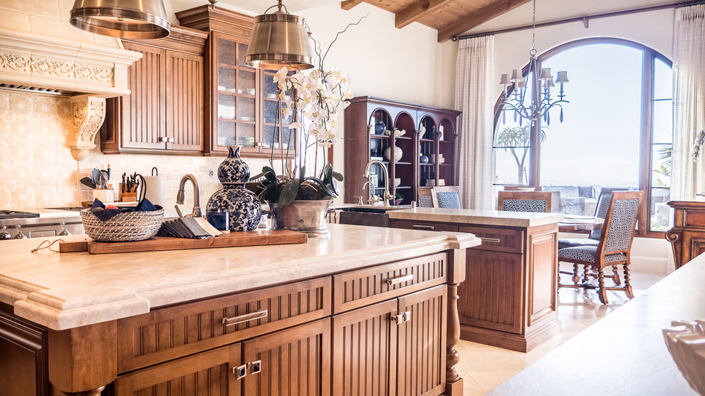 Example of a large transitional u-shaped cement tile floor and beige floor open concept kitchen design in San Diego with a farmhouse sink, glass-front cabinets, dark wood cabinets, granite countertops, beige backsplash, ceramic backsplash and an island