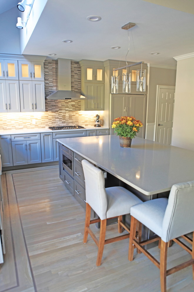 Example of a huge arts and crafts light wood floor eat-in kitchen design in Providence with a single-bowl sink, shaker cabinets, gray cabinets, quartzite countertops, gray backsplash, stone tile backsplash and stainless steel appliances