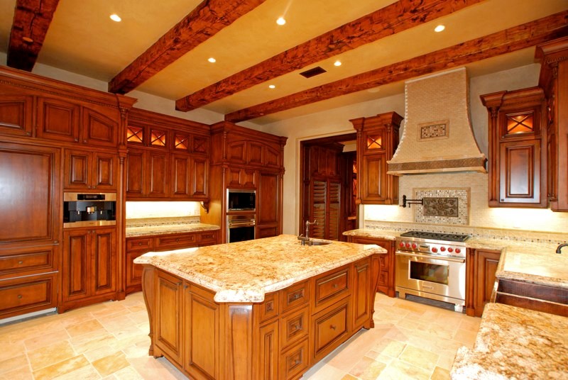 Immagine di una cucina stile rurale chiusa e di medie dimensioni con lavello a doppia vasca, ante con bugna sagomata, ante in legno scuro, top in granito, elettrodomestici in acciaio inossidabile e pavimento in pietra calcarea