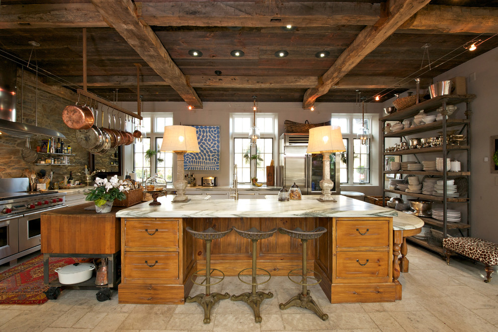 Cette photo montre une cuisine nature en bois vieilli et L avec plan de travail en marbre, une crédence en carrelage de pierre, un électroménager en acier inoxydable et un évier de ferme.