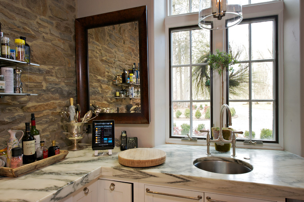 Imagen de cocina de estilo de casa de campo con fregadero sobremueble, puertas de armario con efecto envejecido, encimera de mármol, salpicadero de azulejos de piedra y electrodomésticos de acero inoxidable