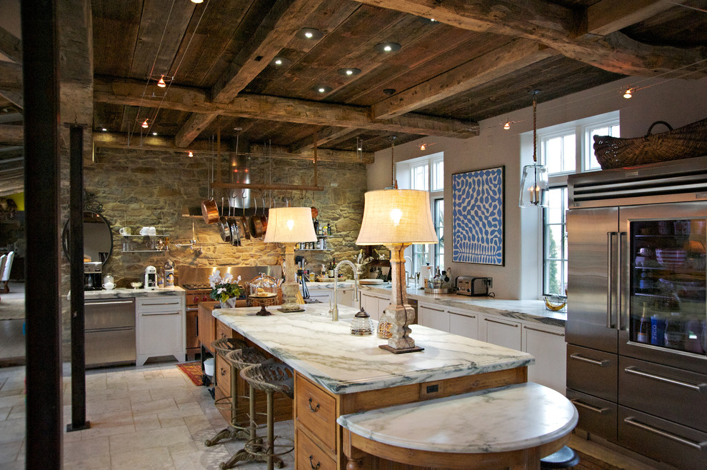 Modelo de cocina de estilo de casa de campo con fregadero sobremueble, encimera de mármol, salpicadero de azulejos de piedra y electrodomésticos de acero inoxidable