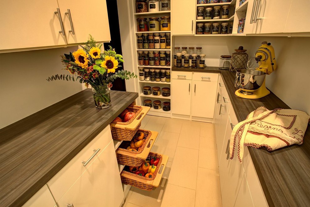 Example of a large trendy porcelain tile kitchen pantry design in New York with flat-panel cabinets, white cabinets and wood countertops