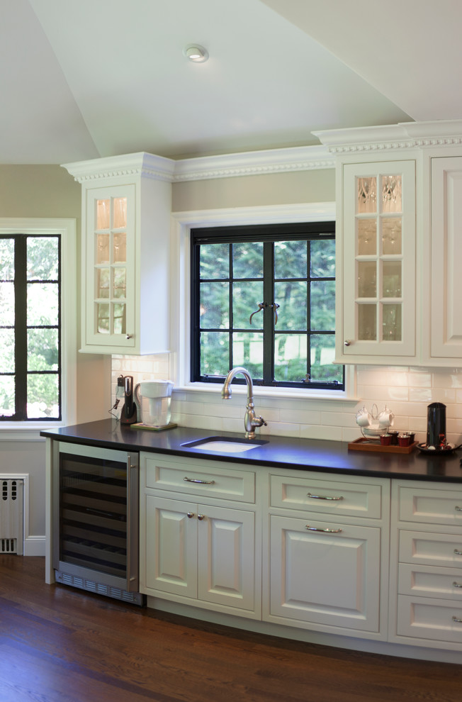 Imagen de cocina comedor clásica con puertas de armario blancas, salpicadero blanco y electrodomésticos de acero inoxidable