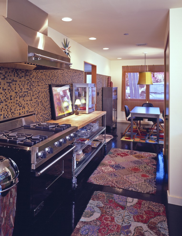 This is an example of a medium sized traditional kitchen in Los Angeles with wood worktops, multi-coloured splashback, mosaic tiled splashback, stainless steel appliances, dark hardwood flooring and brown floors.