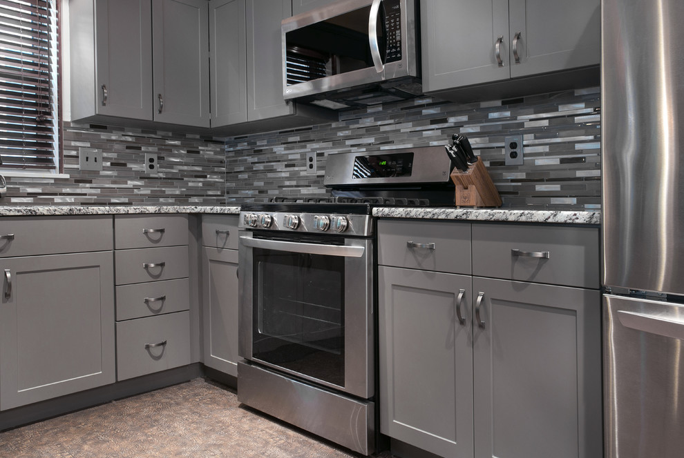 Exempel på ett mellanstort amerikanskt flerfärgad flerfärgat kök, med en dubbel diskho, släta luckor, grå skåp, granitbänkskiva, stänkskydd i mosaik, rostfria vitvaror, klinkergolv i porslin och beiget golv