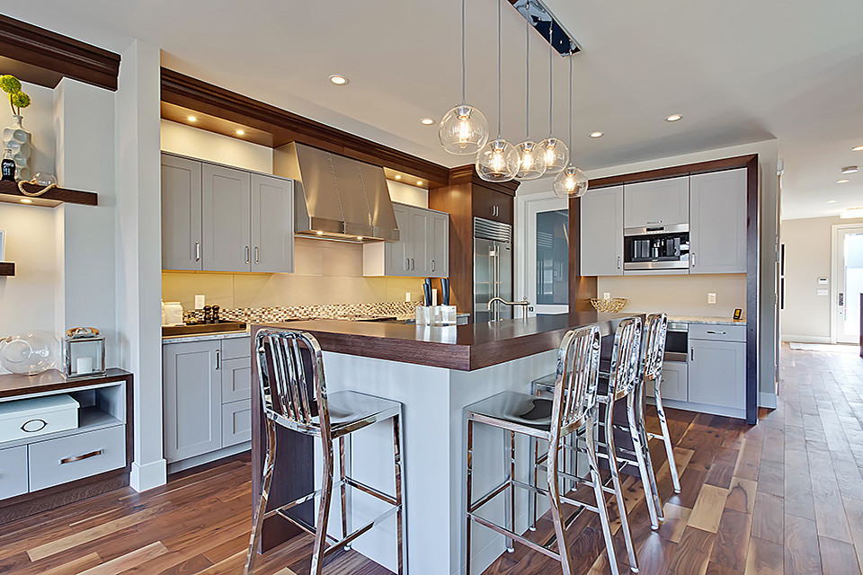 Moderne Küche mit Schrankfronten im Shaker-Stil, grauen Schränken, Küchengeräten aus Edelstahl, hellem Holzboden, Kücheninsel und Arbeitsplatte aus Holz in Calgary