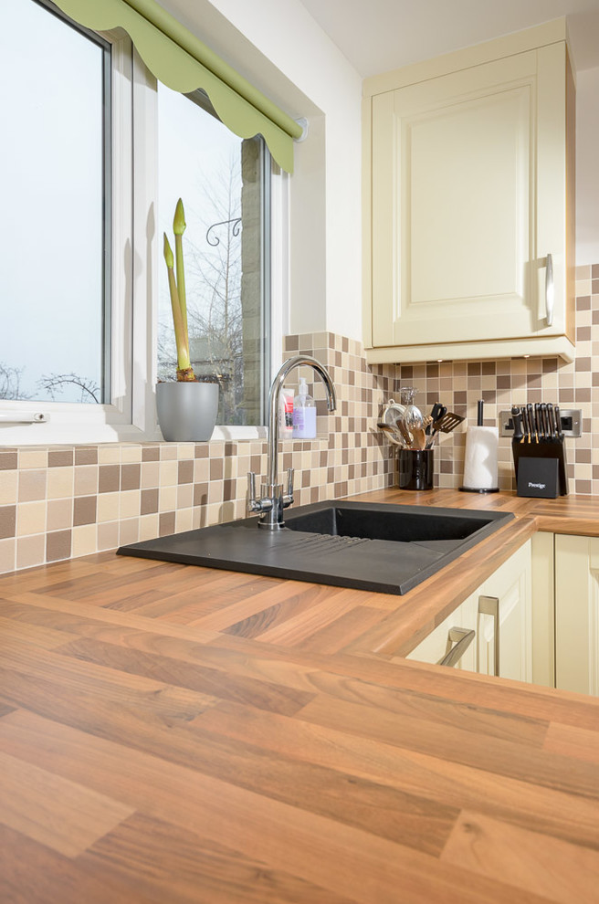 This is an example of a small traditional l-shaped kitchen/diner in Other with light wood cabinets, wood worktops, brown splashback, terracotta splashback, integrated appliances, lino flooring and a breakfast bar.