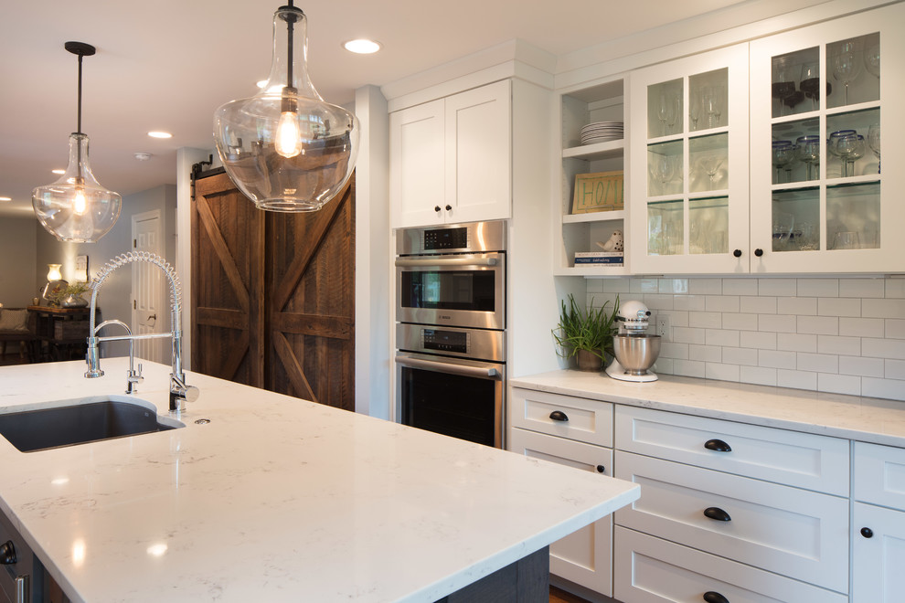 Exempel på ett mellanstort rustikt kök, med en undermonterad diskho, skåp i shakerstil, vita skåp, bänkskiva i kvarts, vitt stänkskydd, stänkskydd i tunnelbanekakel, rostfria vitvaror, mellanmörkt trägolv, en köksö och brunt golv