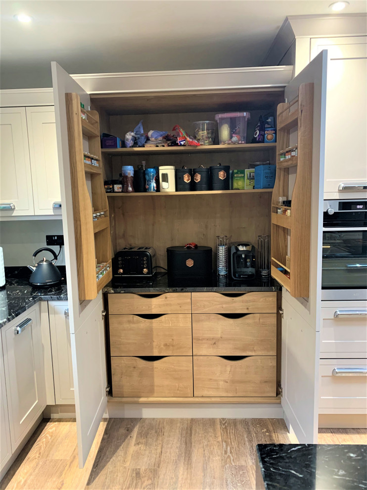 Large classic u-shaped open plan kitchen in Other with a double-bowl sink, shaker cabinets, medium wood cabinets, granite worktops, black splashback, black appliances, vinyl flooring, an island and black worktops.
