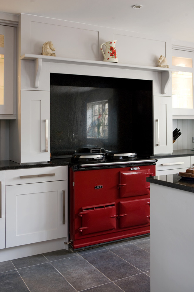 На фото: кухня в стиле неоклассика (современная классика) с фасадами в стиле шейкер, белыми фасадами, черным фартуком, фартуком из каменной плиты и цветной техникой с