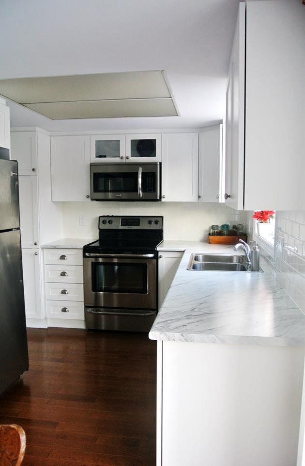 Esempio di una piccola cucina minimal con lavello a doppia vasca, ante in stile shaker, ante bianche, top in laminato, paraspruzzi bianco e pavimento in legno massello medio
