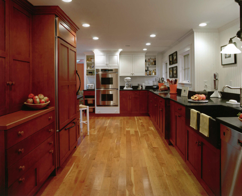 Exemple d'une grande cuisine américaine encastrable chic en bois brun avec îlot, un évier 1 bac, un plan de travail en granite, une crédence blanche, parquet clair et un sol marron.