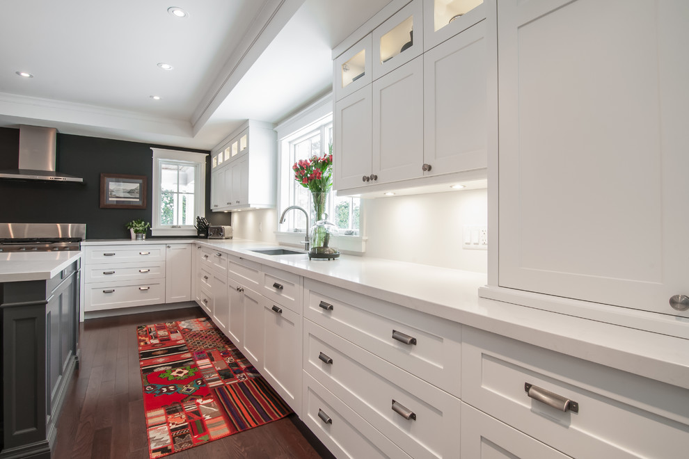 Minimalist l-shaped dark wood floor enclosed kitchen photo in Toronto with an undermount sink, shaker cabinets, white cabinets, marble countertops, white backsplash, stainless steel appliances and an island