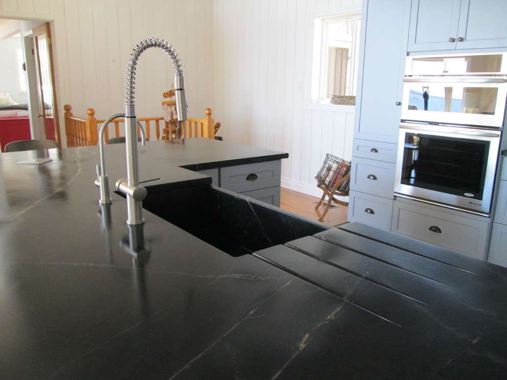 Example of a cottage chic slate floor kitchen design in Toronto with an undermount sink, shaker cabinets, gray cabinets, soapstone countertops, white backsplash, glass tile backsplash, stainless steel appliances and an island