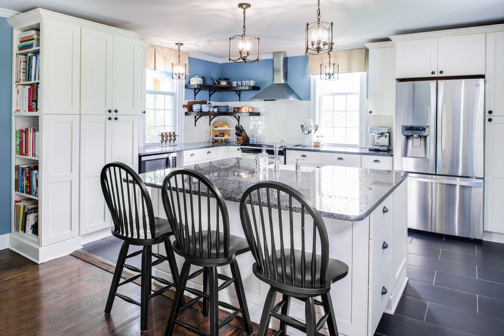 Open concept kitchen - mid-sized transitional l-shaped porcelain tile and black floor open concept kitchen idea in New York with a farmhouse sink, shaker cabinets, white cabinets, granite countertops, white backsplash, subway tile backsplash, stainless steel appliances and an island