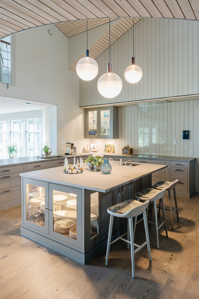 На фото: п-образная кухня-гостиная в скандинавском стиле с фасадами с утопленной филенкой, серыми фасадами, светлым паркетным полом и островом с