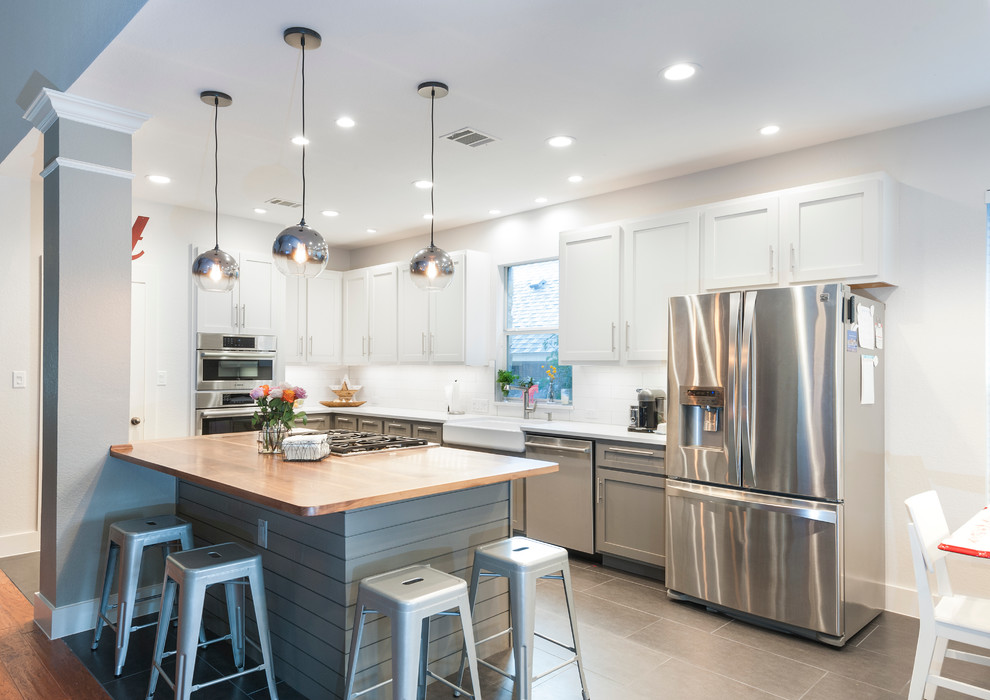 Example of a large trendy l-shaped ceramic tile open concept kitchen design in Austin with a farmhouse sink, shaker cabinets, white cabinets, wood countertops, white backsplash, ceramic backsplash, stainless steel appliances and an island