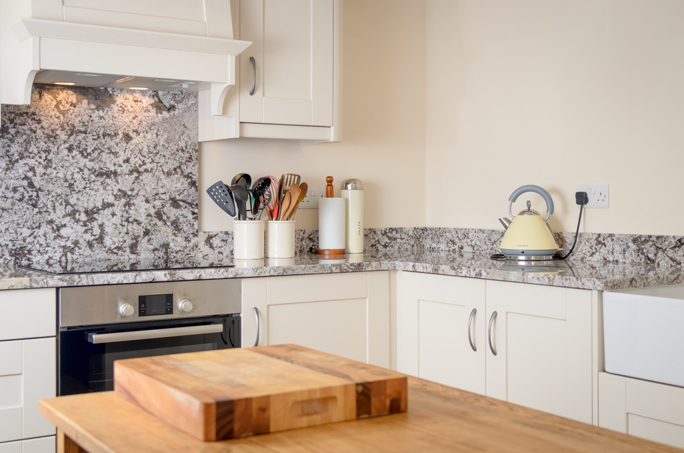 Exempel på ett mellanstort rustikt kök, med en rustik diskho, vita skåp, granitbänkskiva, grått stänkskydd och rostfria vitvaror