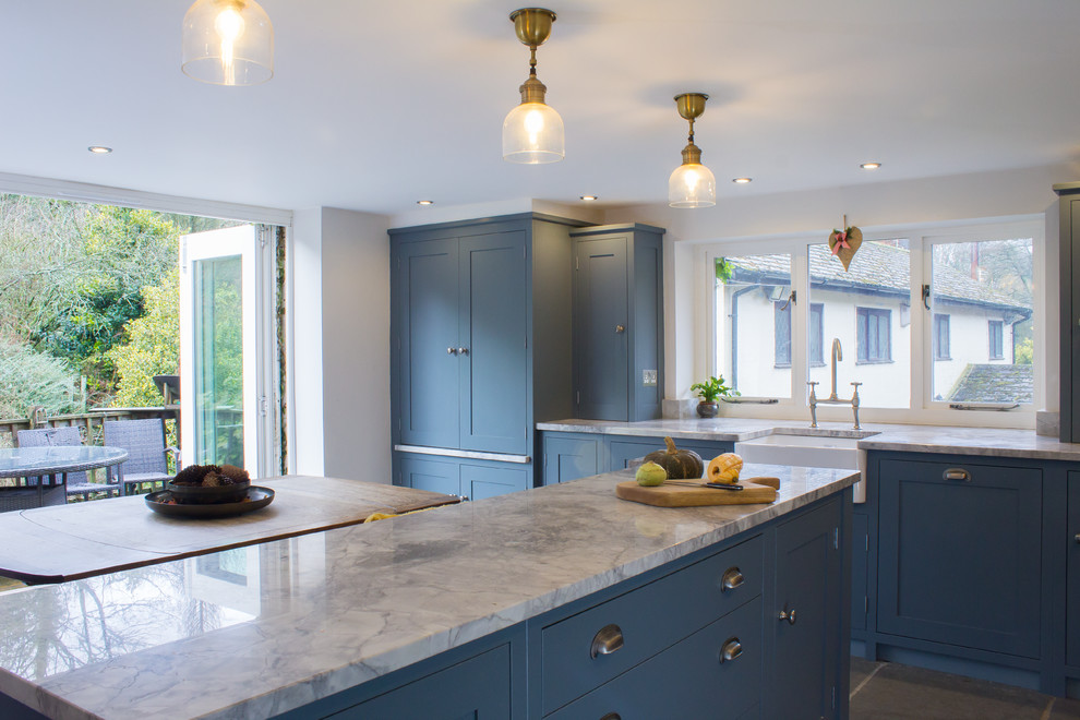 This is an example of a medium sized traditional l-shaped kitchen/diner in Manchester with a belfast sink, shaker cabinets, grey cabinets, granite worktops, grey splashback, stainless steel appliances, an island and grey floors.