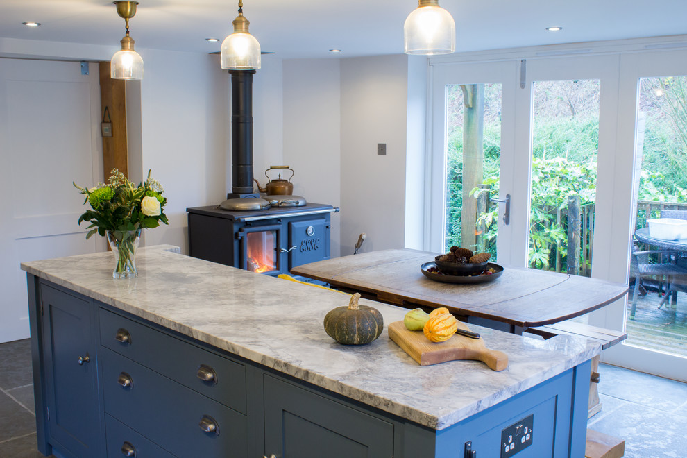 Photo of a medium sized traditional l-shaped kitchen/diner in Manchester with a belfast sink, shaker cabinets, grey cabinets, granite worktops, grey splashback, stainless steel appliances, an island and grey floors.