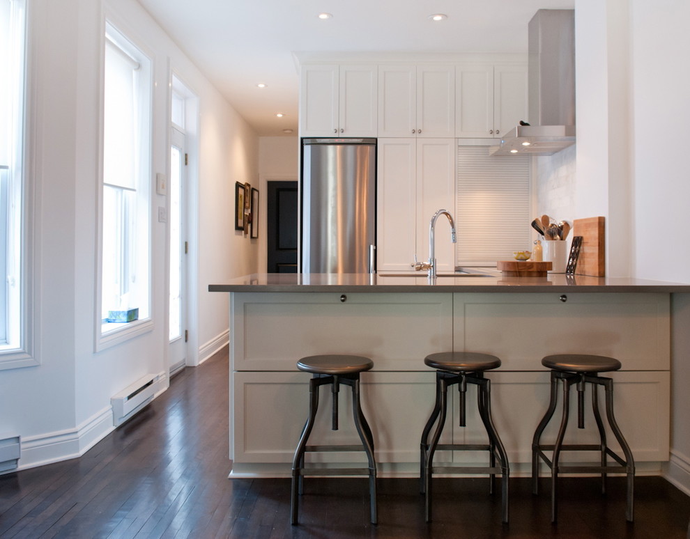 Offene Klassische Küche in U-Form mit Schrankfronten mit vertiefter Füllung, weißen Schränken, Küchenrückwand in Weiß und Küchengeräten aus Edelstahl in Montreal