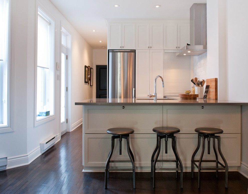 Example of a transitional u-shaped open concept kitchen design in Montreal with recessed-panel cabinets, white cabinets, white backsplash and stainless steel appliances