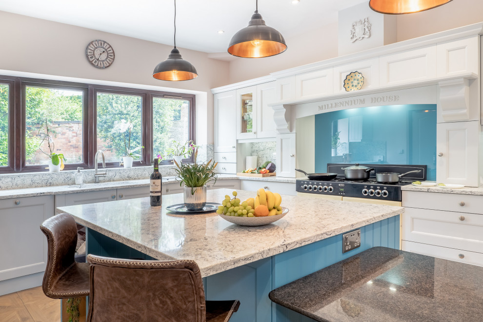Exemple d'une grande cuisine chic en L avec îlot, un placard avec porte à panneau encastré, des portes de placard blanches, une crédence bleue, une crédence en feuille de verre, un sol beige et un plan de travail multicolore.