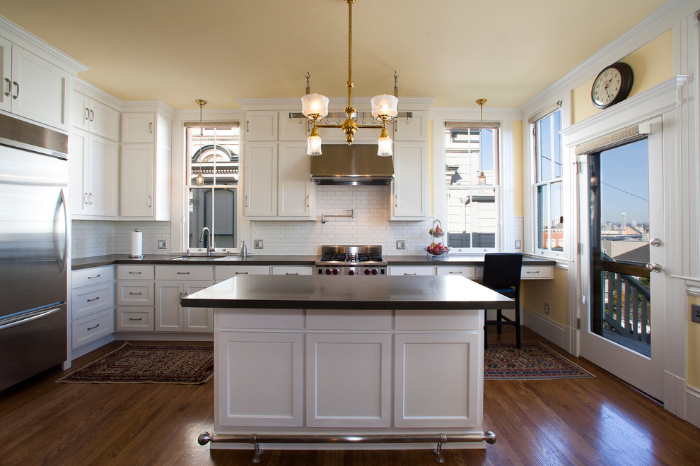 Inspiration for a mid-sized timeless l-shaped eat-in kitchen remodel in San Francisco with shaker cabinets, white cabinets, white backsplash, subway tile backsplash, stainless steel appliances and an island