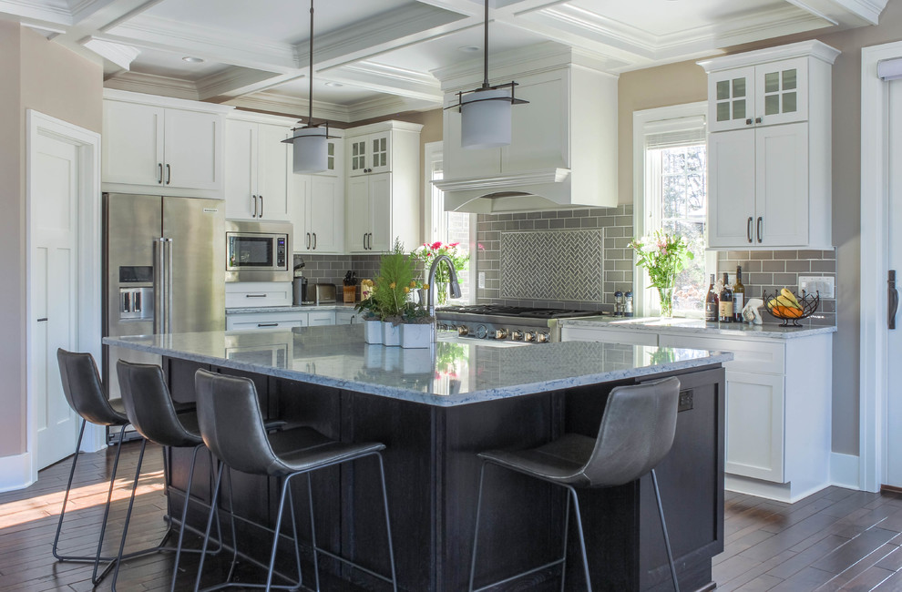 Inspiration for a large transitional l-shaped dark wood floor and brown floor eat-in kitchen remodel in Detroit with a farmhouse sink, shaker cabinets, white cabinets, quartz countertops, gray backsplash, glass tile backsplash, stainless steel appliances, an island and gray countertops