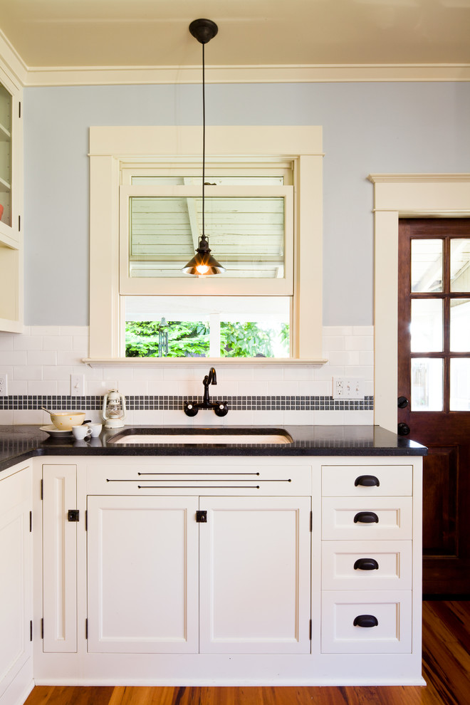 Modelo de cocina tradicional con fregadero bajoencimera, armarios con paneles empotrados, puertas de armario blancas, salpicadero blanco y salpicadero de azulejos tipo metro