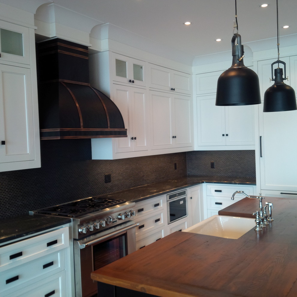 Inspiration for a large cottage l-shaped medium tone wood floor and brown floor eat-in kitchen remodel in Toronto with a farmhouse sink, shaker cabinets, white cabinets, wood countertops, gray backsplash, mosaic tile backsplash, paneled appliances and an island