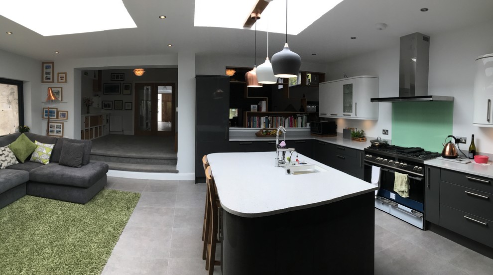 Bild på ett stort funkis kök, med en undermonterad diskho, släta luckor, grå skåp, bänkskiva i kvarts, grönt stänkskydd, glaspanel som stänkskydd, integrerade vitvaror, linoleumgolv, en köksö och grått golv