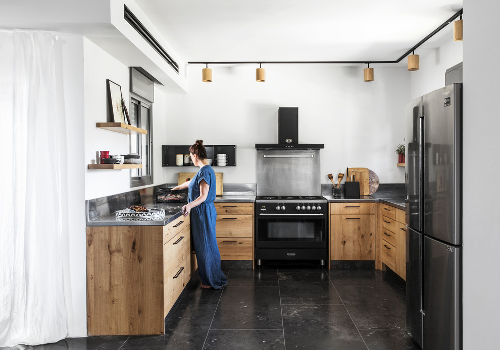 Modelo de cocinas en U ecléctico con armarios con paneles lisos, encimera de acero inoxidable, salpicadero metalizado, electrodomésticos negros y suelo negro