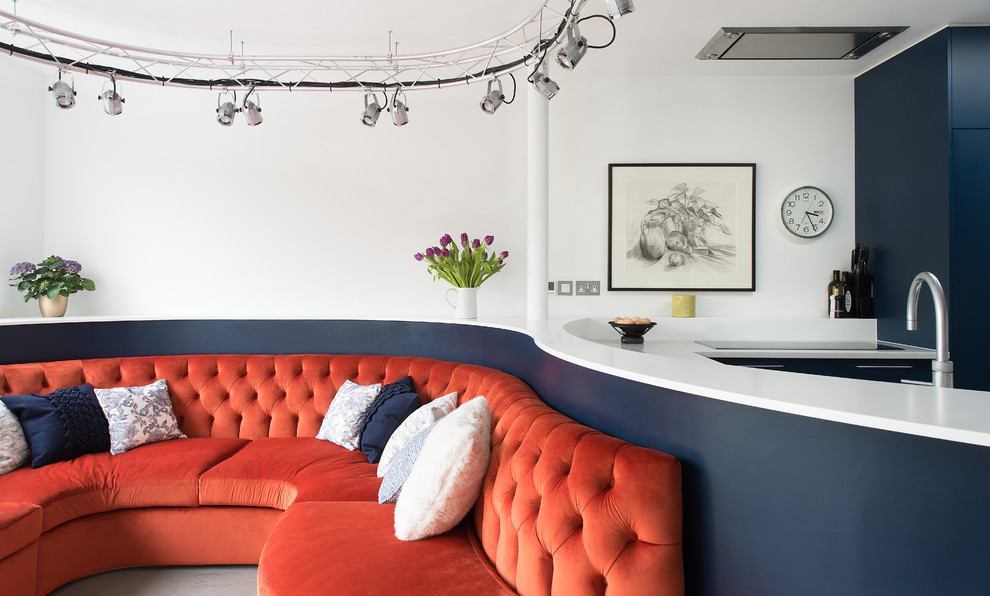 ロンドンにある高級な中くらいなエクレクティックスタイルのおしゃれなキッチン (ダブルシンク、フラットパネル扉のキャビネット、青いキャビネット、人工大理石カウンター、パネルと同色の調理設備、コンクリートの床) の写真