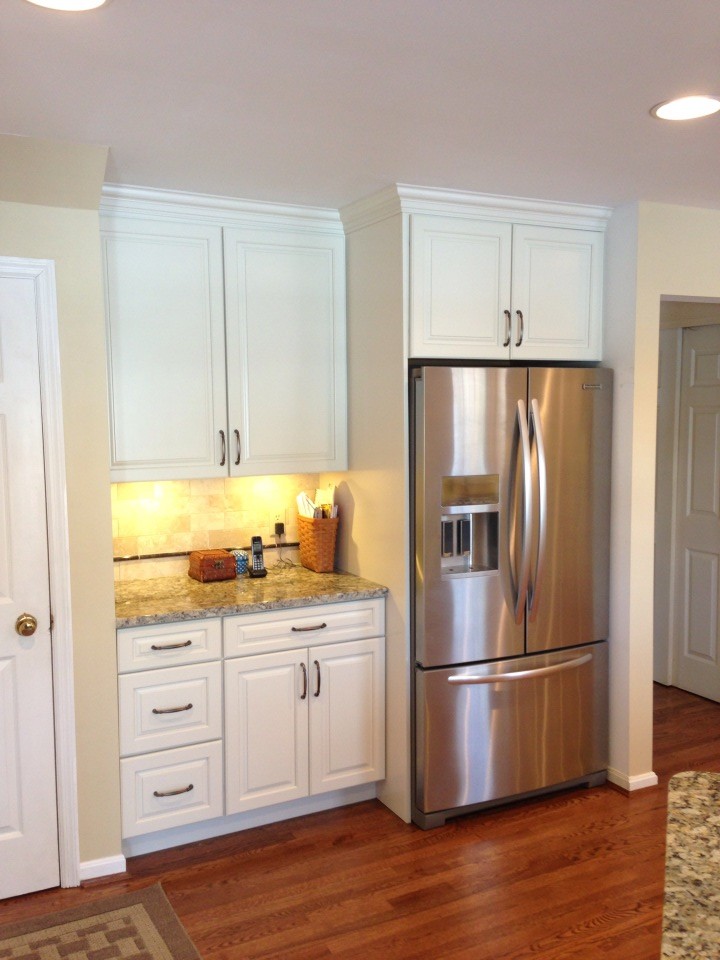 Exempel på ett avskilt, mellanstort klassiskt u-kök, med en undermonterad diskho, luckor med upphöjd panel, vita skåp, granitbänkskiva, beige stänkskydd, stänkskydd i tunnelbanekakel, rostfria vitvaror, ljust trägolv och en halv köksö